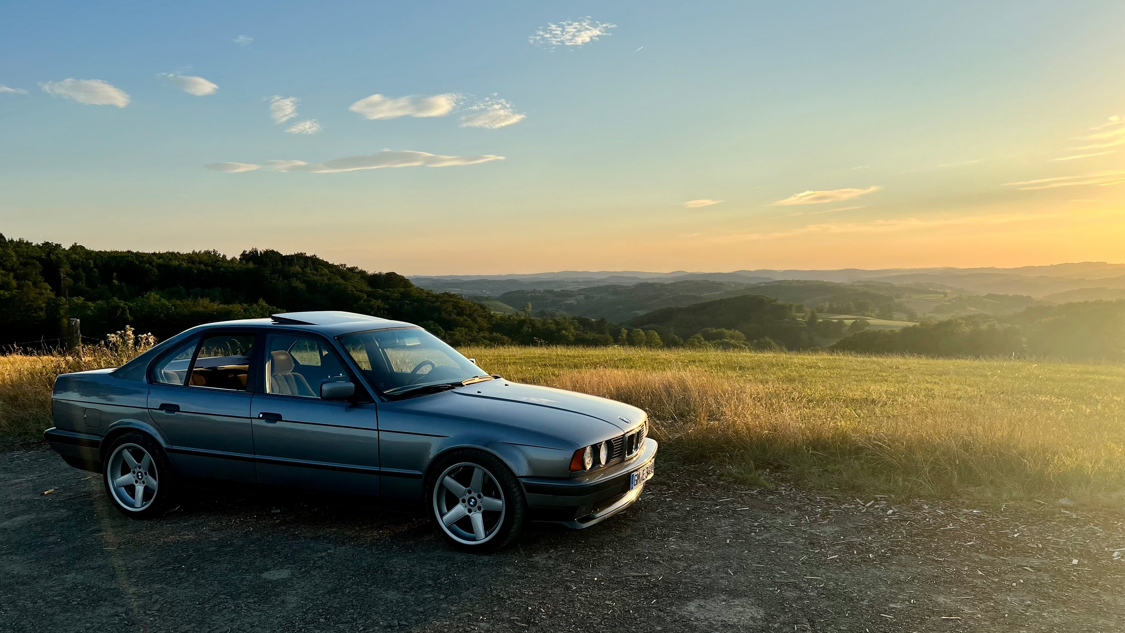 Ein getunter BMW E34 vor einer großen Landschaft.