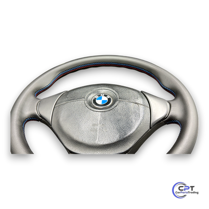 Detailaufnahme: M-Ziernaht auf schwarzem Leder am unteren Bereich des Lenkrads

